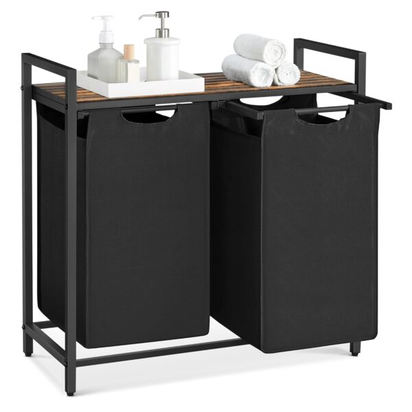 Ein doppelter Wäschekorb mit schwarzen Stoffbehältern, einem Metallrahmen und einer Holzplatte für Toilettenartikel und gerollte Handtücher. VASAGLE Wäschekorb 2‑fach, abnehmbarer Sack, Metallrahmen, tintenschwarz‑Vintage